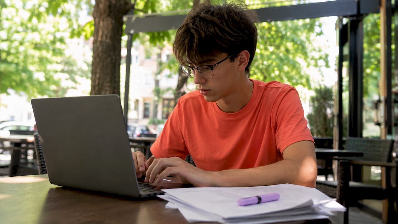 Student typing draft on laptop at library